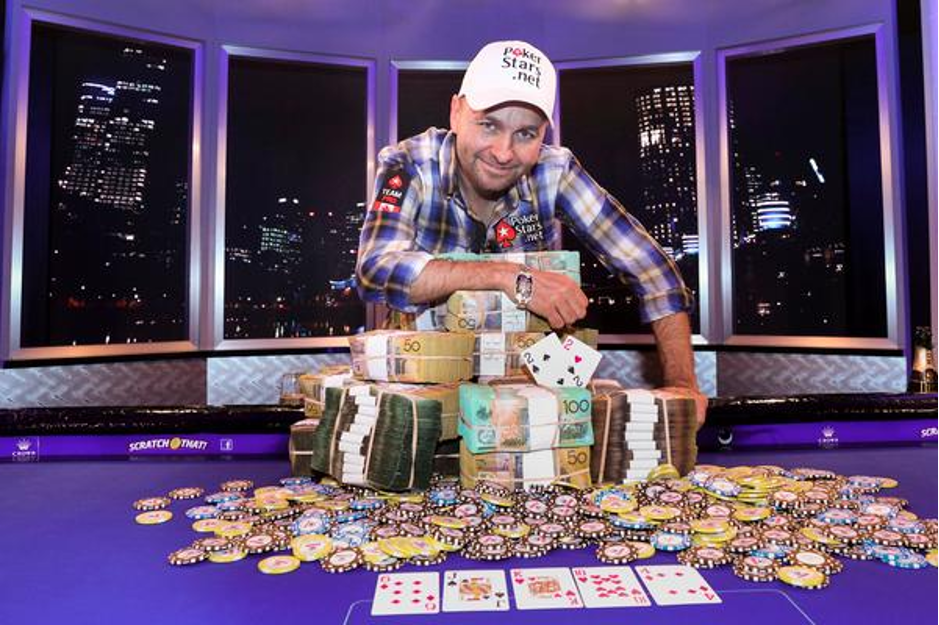 Daniel Negreanu standing over a large sum of poker chips and money and his winning hand